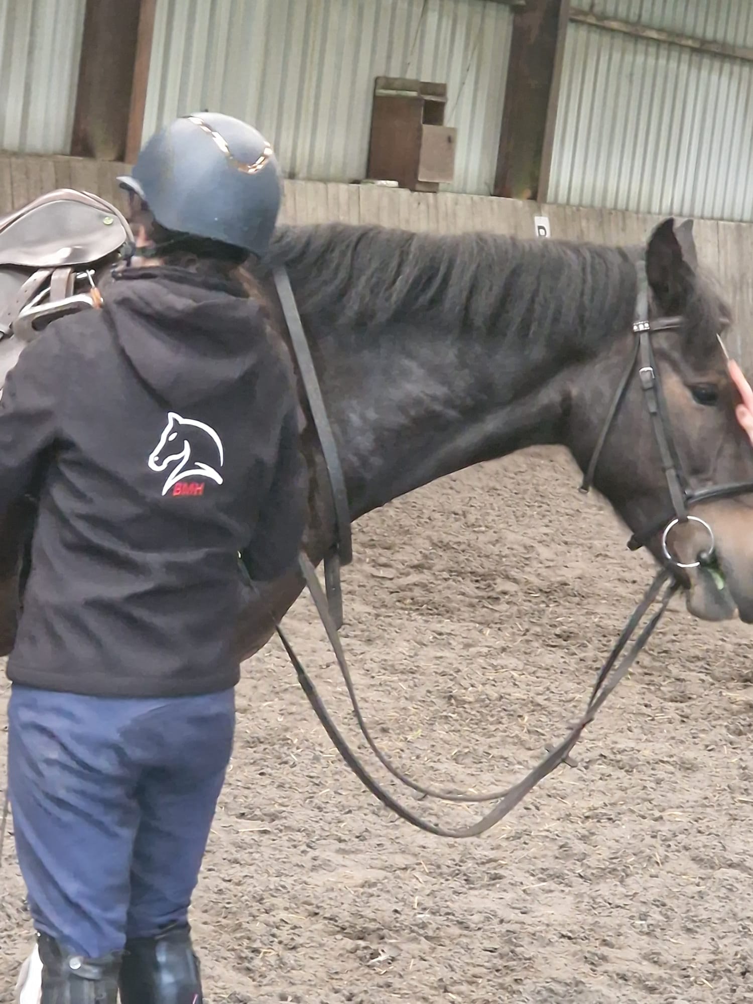 Bianca in her BMH jacket working with a black horse in the arena